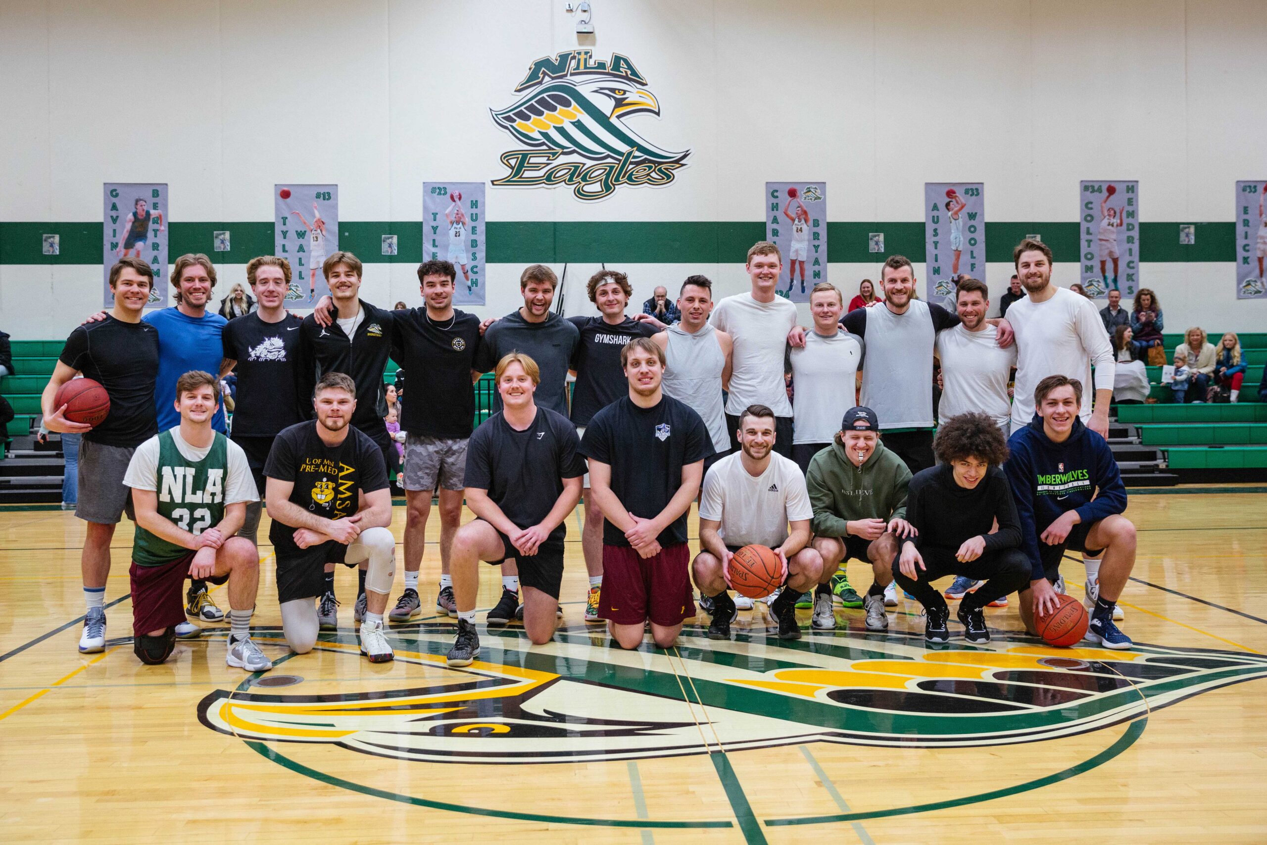 New Life Academy alumni basketball players posing together on the school gym court during an alumni game.