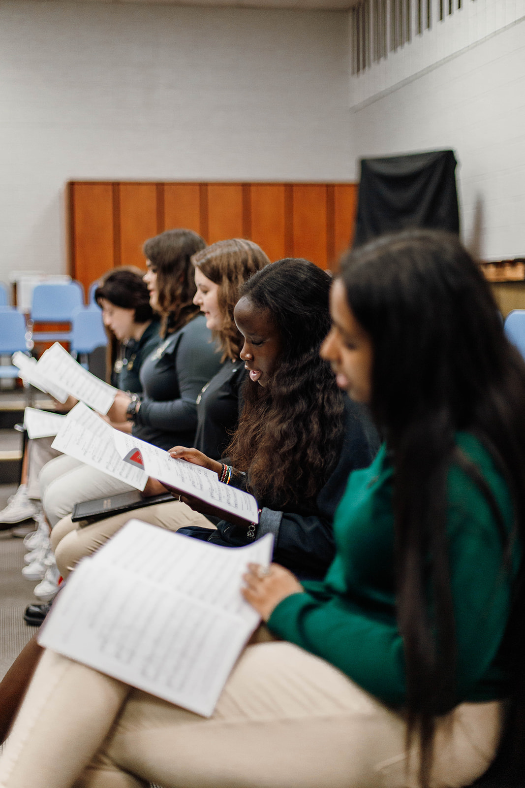 New Life Academy choir students rehearsing with music folders in the choir room.