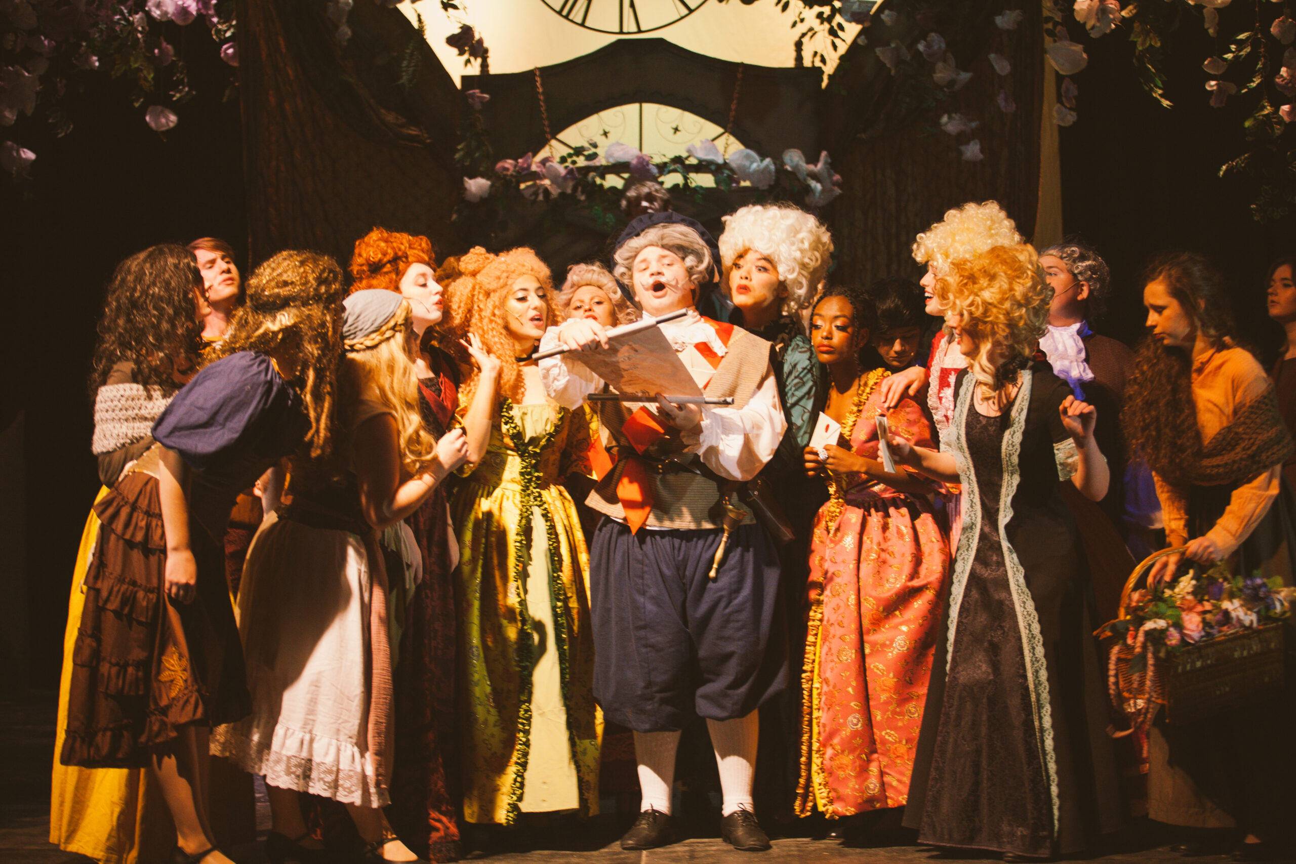 New Life Academy theatre cast performing a musical ensemble scene from the school’s production of Cinderella, dressed in ornate period-style costumes.