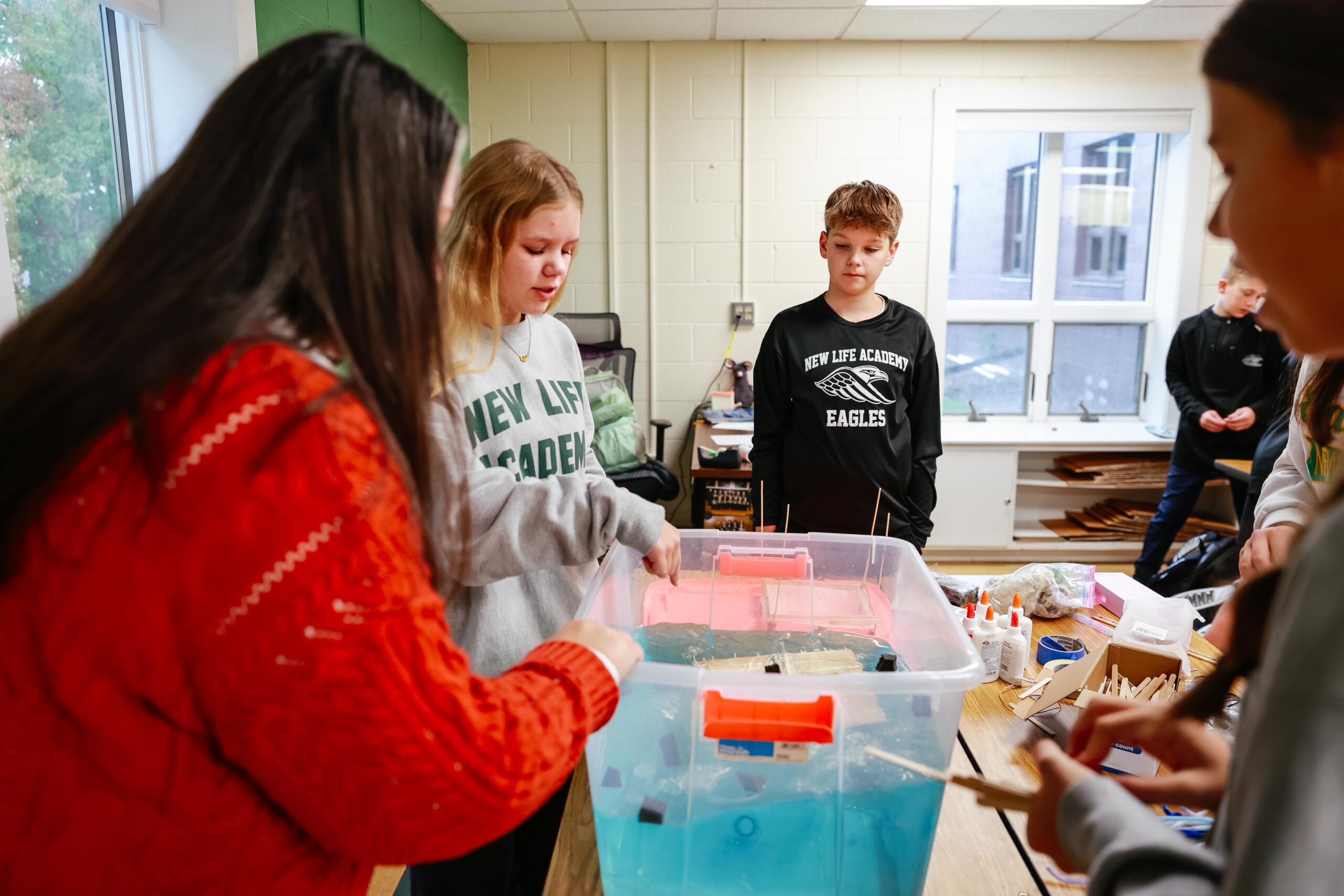 Middle school students at New Life Academy work together on a prototype designed to collect plastic from the ocean during a hands-on science lesson