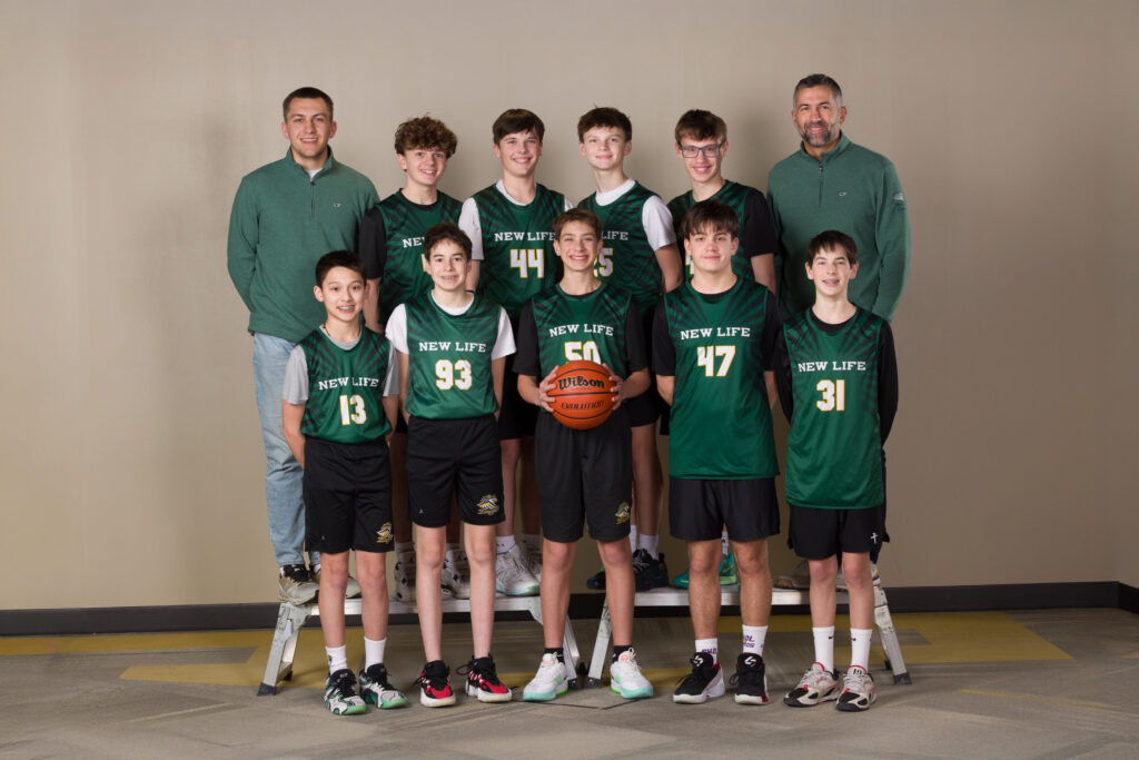 Middle school basketball team from New Life School posing together in green team jerseys for a team photo.