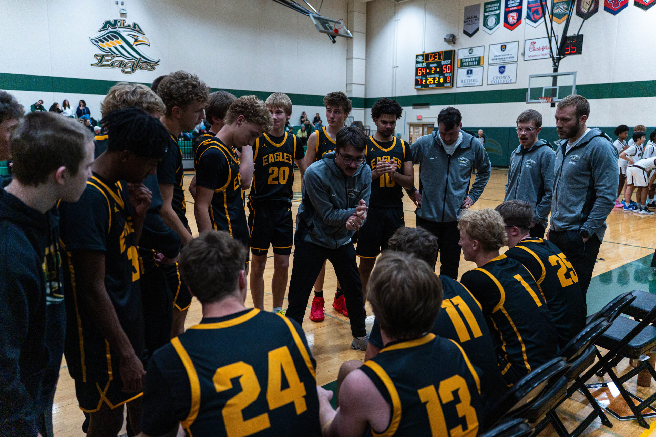 New Life Academy boys varsity basketball team huddled together on the court before a game.
